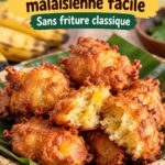 Beignets de banane écrasée dorés, une gourmandise malaisienne sur une assiette en bois.